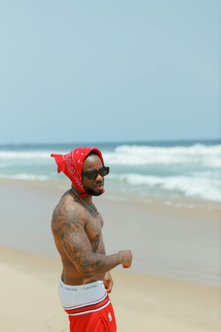 A shirtless man in sunglasses and a bandana enjoys a sunny day on Lagos Beach, Nigeria.