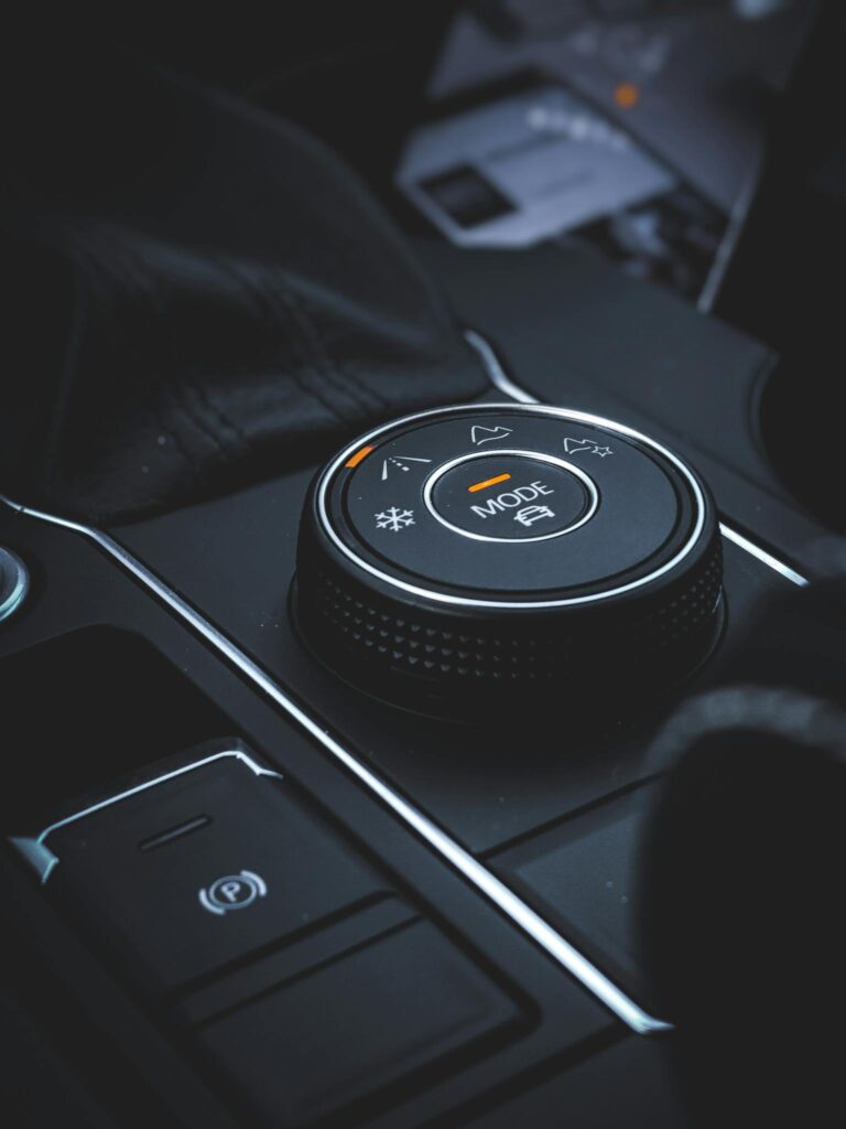 Detailed view of a car mode selector knob in a modern vehicle interior featuring technology and control elements.